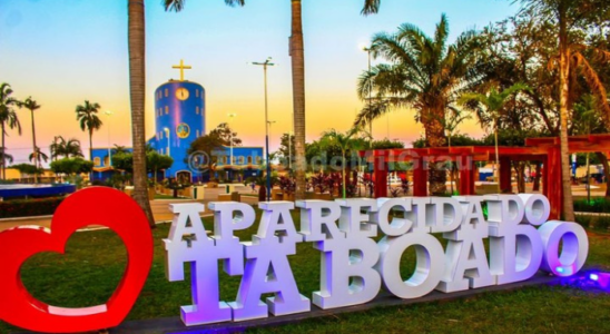 Letreiro na praça e ao fundo a Igreja Matriz de Aparecida do Taboado.